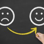 Hand Drawing Unhappy And Happy Smileys On Blackboard